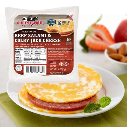 Halal Colby Jack Cheesewich™ and Beef Salami package with product on plate on a modern green placemat and fresh strawberries and almonds slightly blurred out in background.